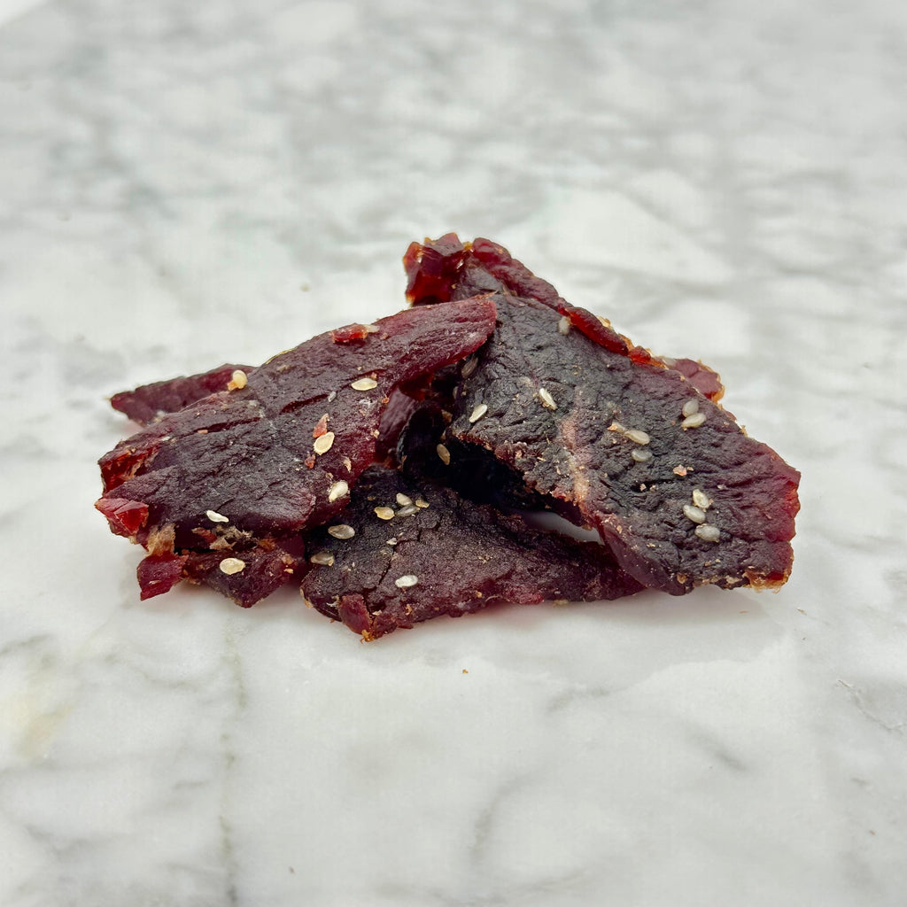 Korean BBQ beef jerky pieces with sesame seeds on marble