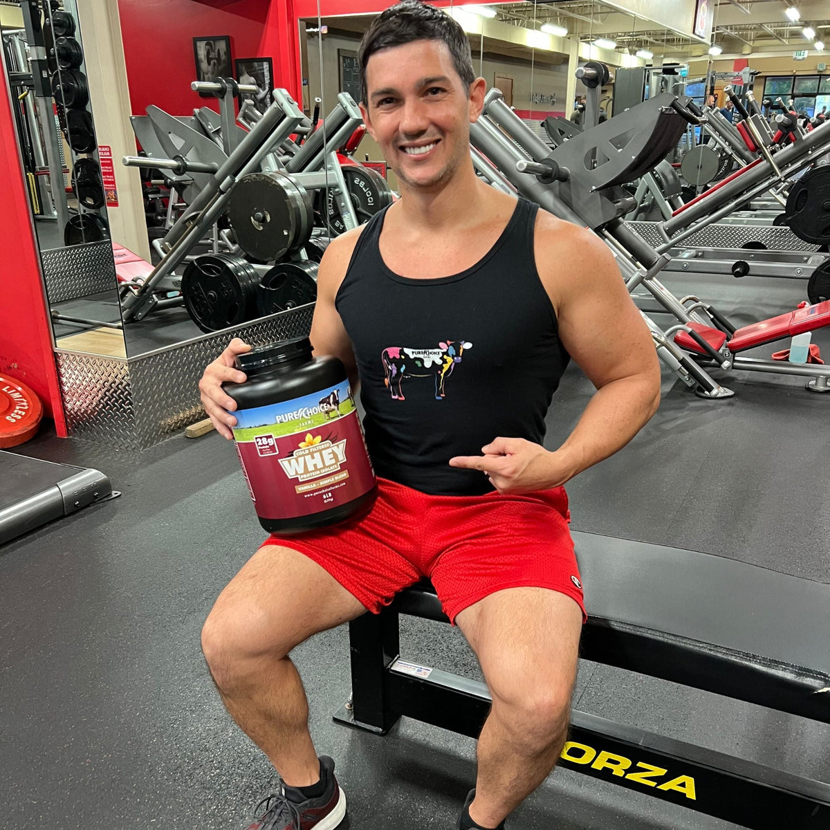 Man in a gym holding a Pure Choice Farms whey protein isolate tub